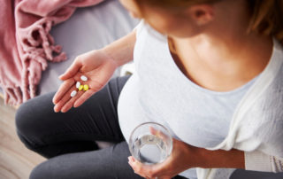 Schwangere Frau nimmt verschiedene Tabletten ein